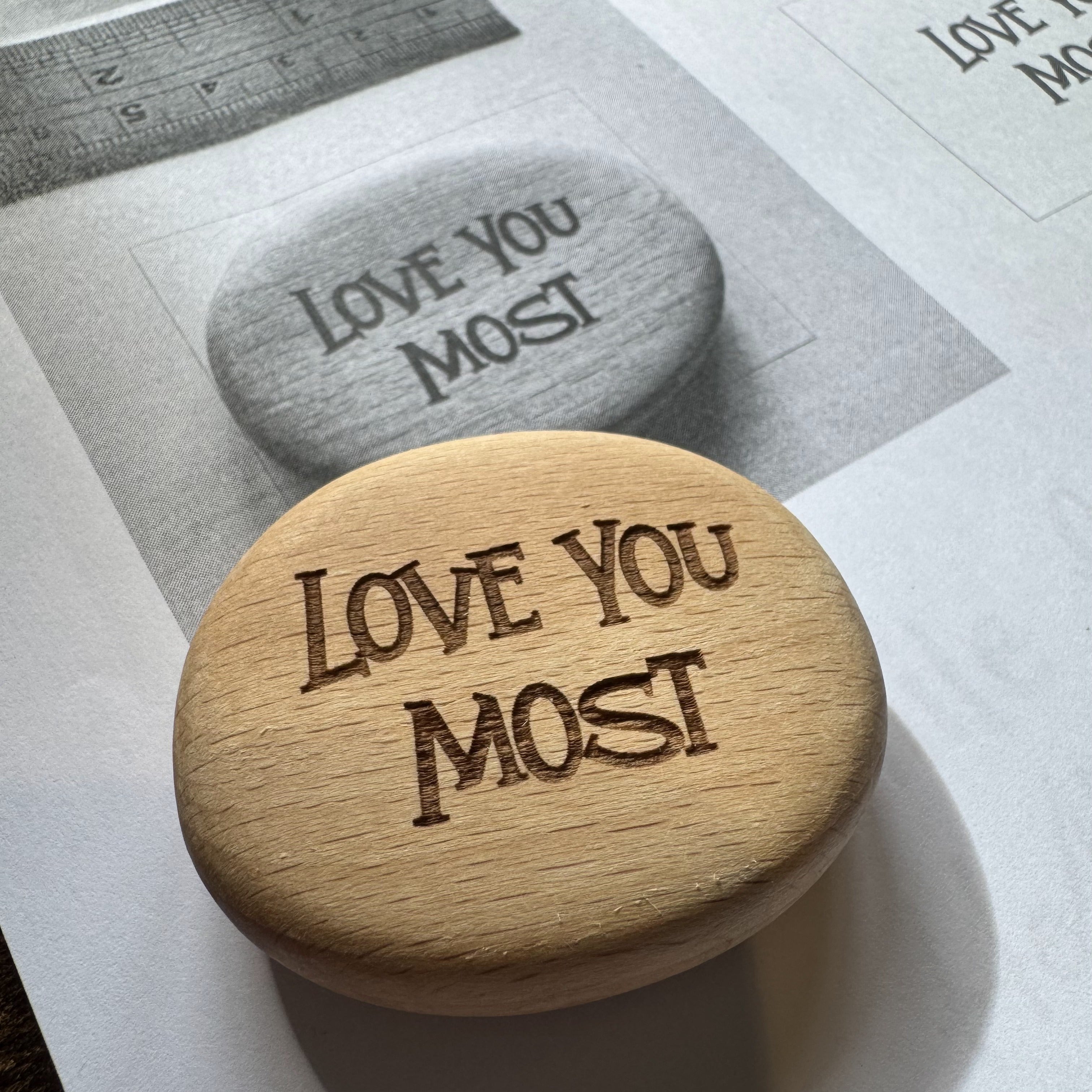 Bespoke double-sided Pocket Pebble with “Love You Most / Love You More” shown against its proof