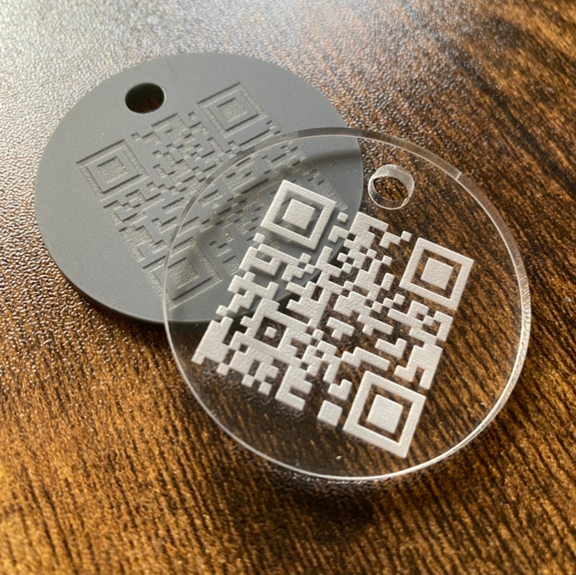 Laser engraved QR code keyrings displayed on desk surface