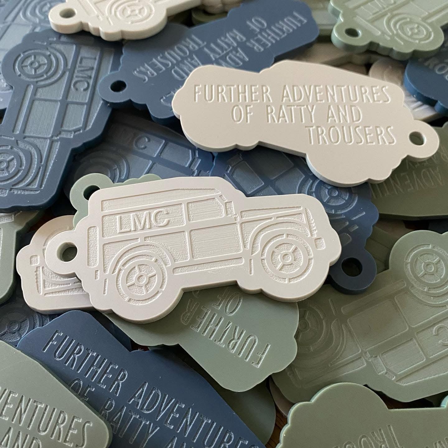 Scatter pile of bespoke double sided engraved club merchandise keyrings in mixed matt colours 
