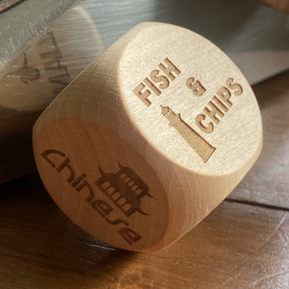 Angled shot of Takeout Decision Dice with 'Fish & Chips' engraving on a home wooden table