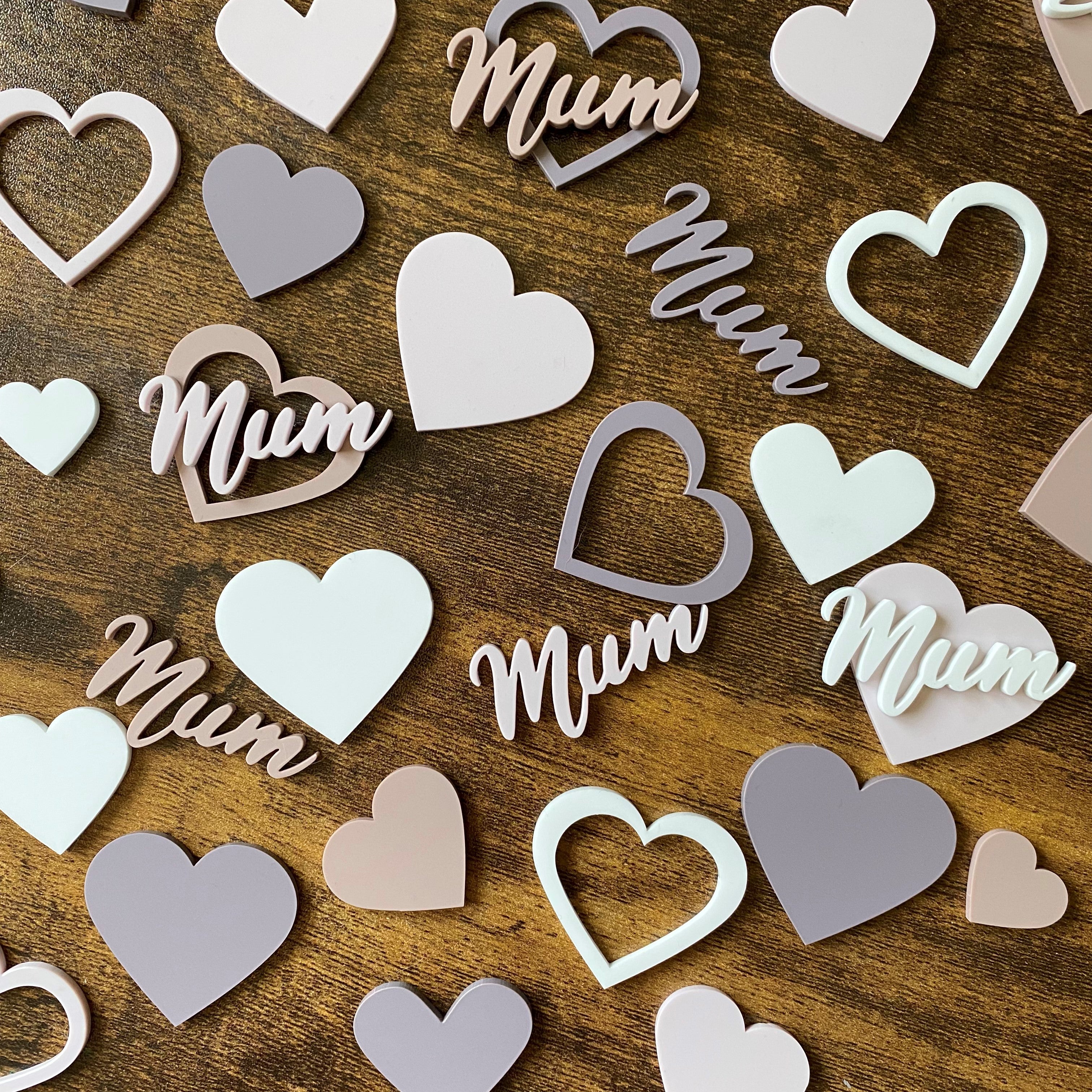 Top-down scatter view of acrylic cake charms featuring love hearts and mum text