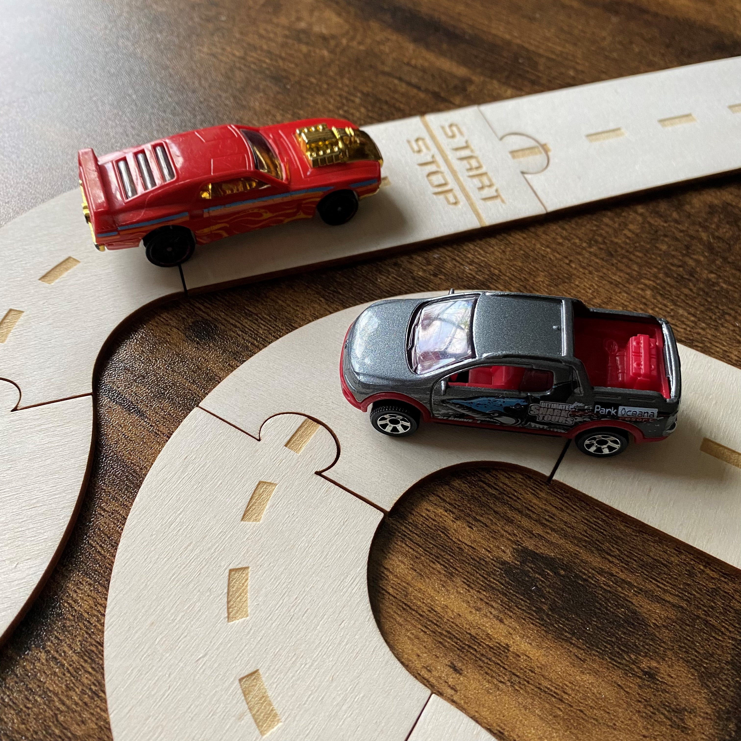 Close-up view of wooden travel track with toy cars, highlighting engraved road detailing and portable play design