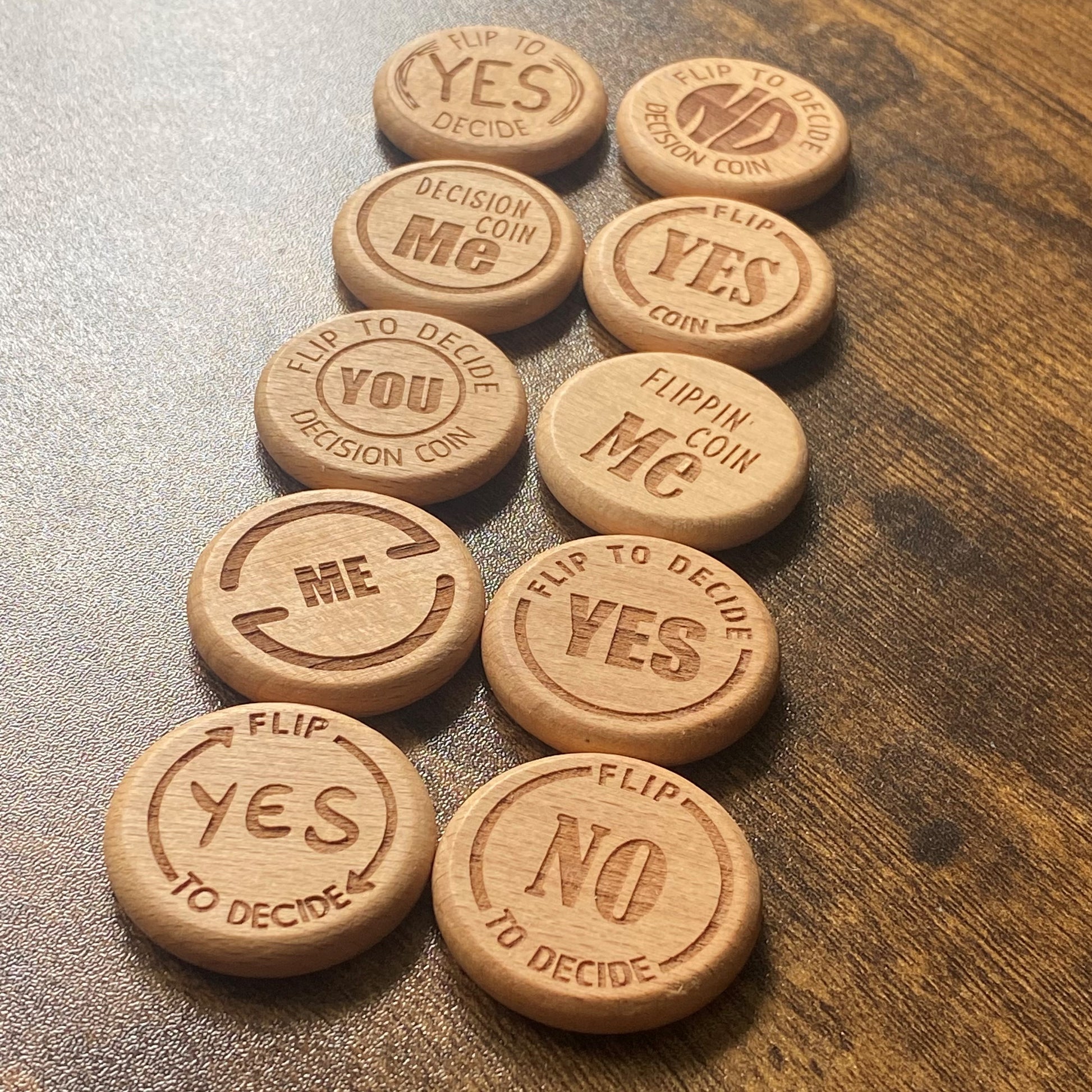An overhead shot of the Ultimate Decision Maker Coin collection, featuring various engraved designs on solid wood