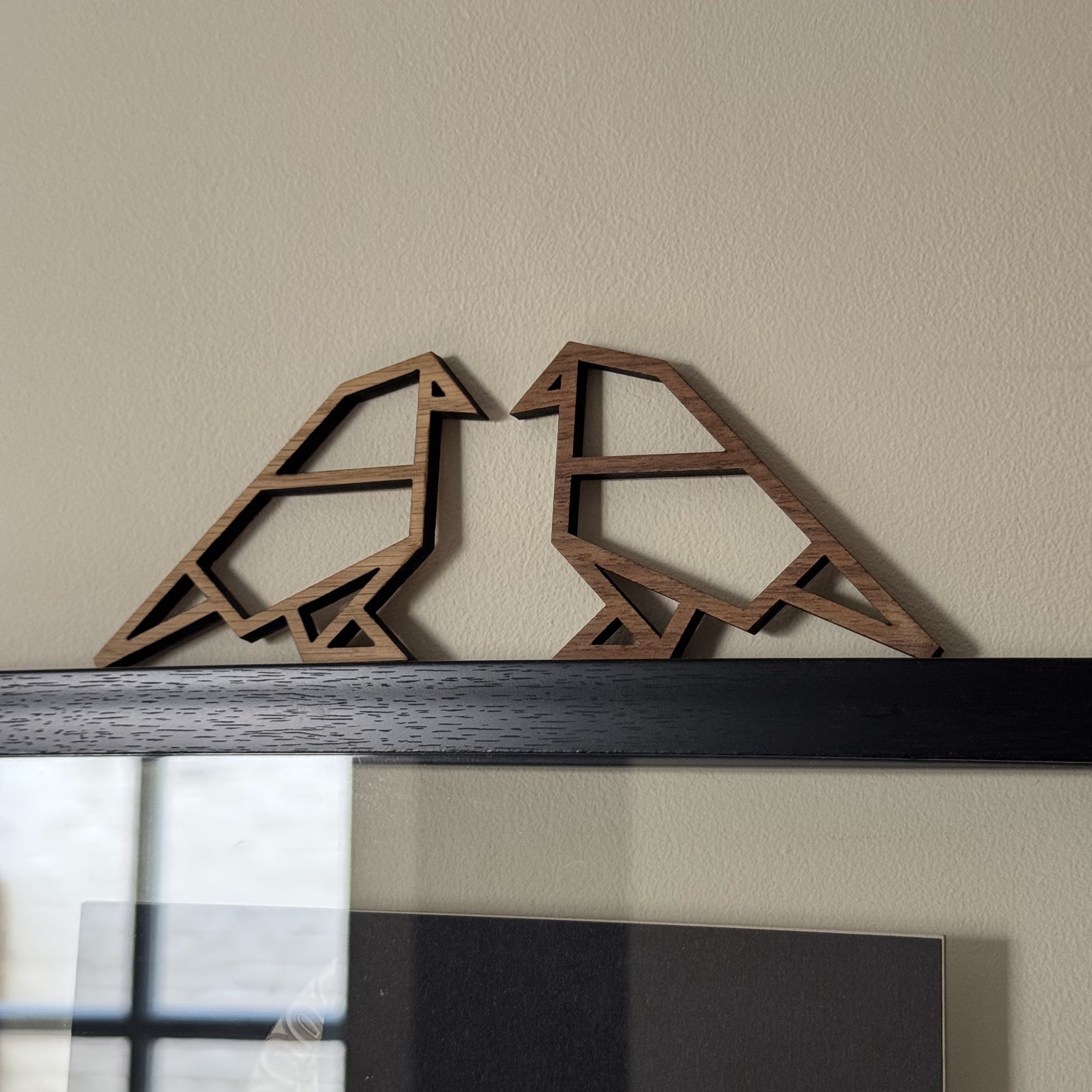 Minimalist bird pair resting on picture frame – wooden sculptures inspired by origami lines
