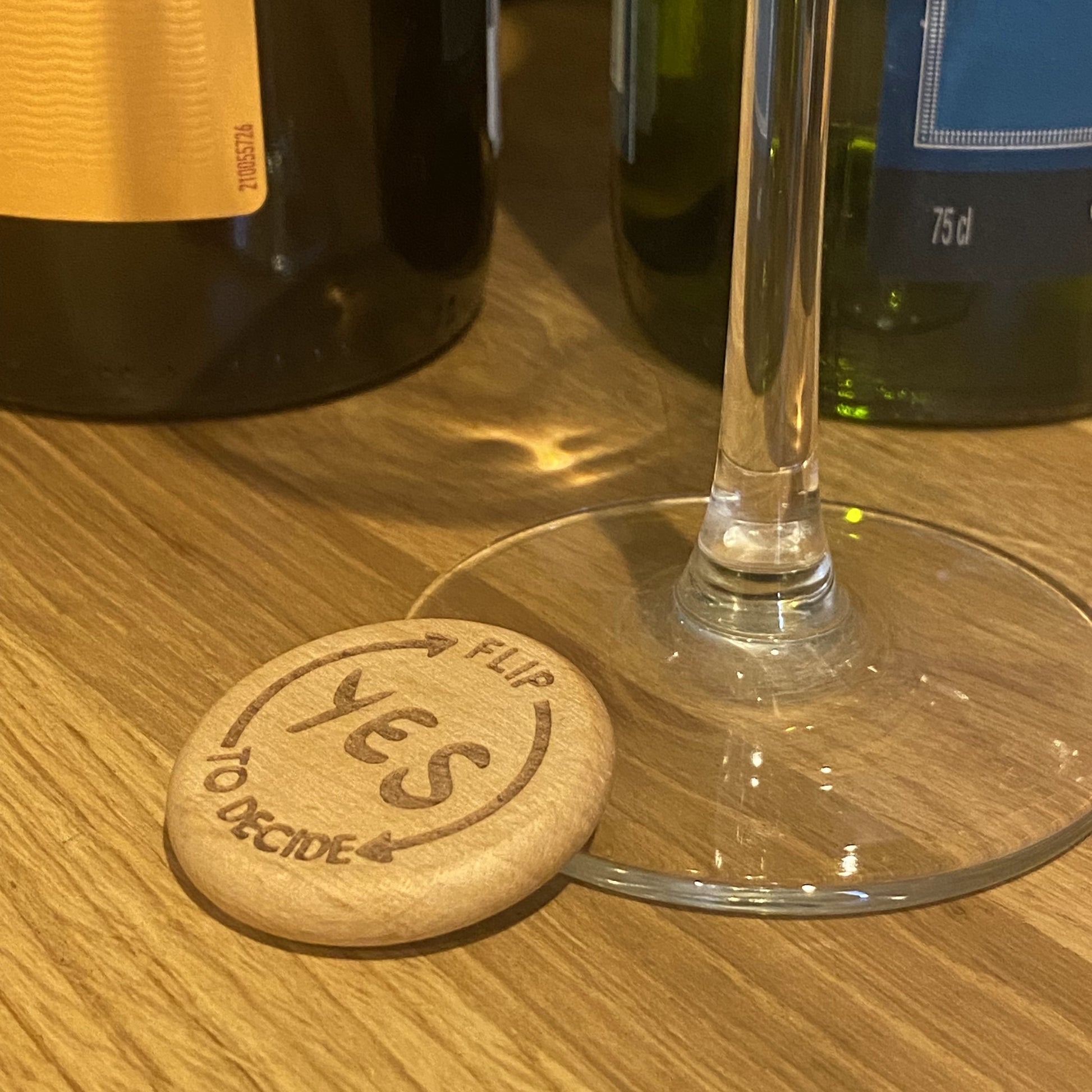 Yes No Ultimate Flip to Decide Coin placed beside wine bottle and glass stem – playful decision maker
