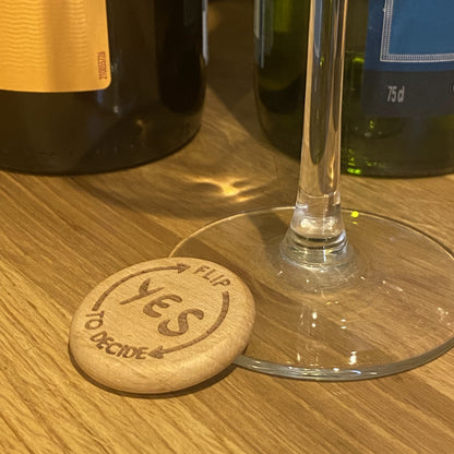 Yes No Ultimate Flip to Decide Coin placed beside wine bottle and glass stem – playful decision maker